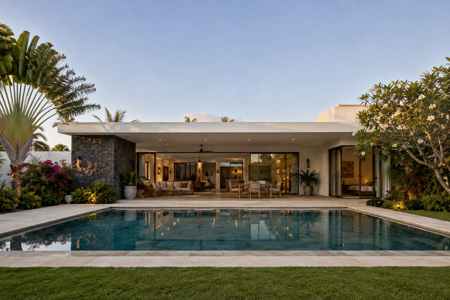 The villa at dusk with the interior lit and the pool still